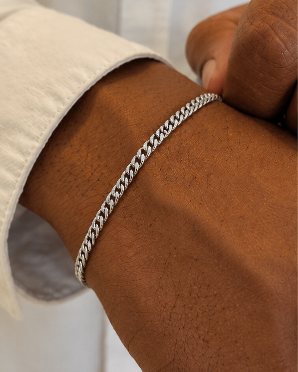Silver chain bracelet on a wrist with a neutral background